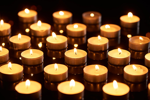 selective focus of burning candles glowing in darkness