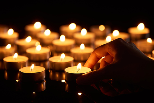 selective focus of woman holding burning candle in darkness