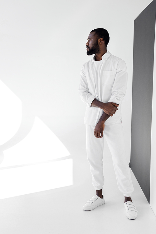 handsome african american man in white trendy clothes looking away