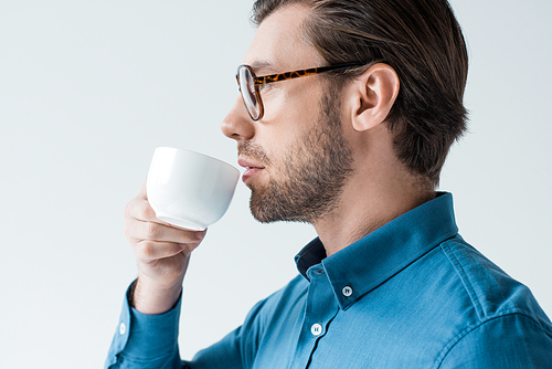 side view of young man drinking coffee from cup isolated on white