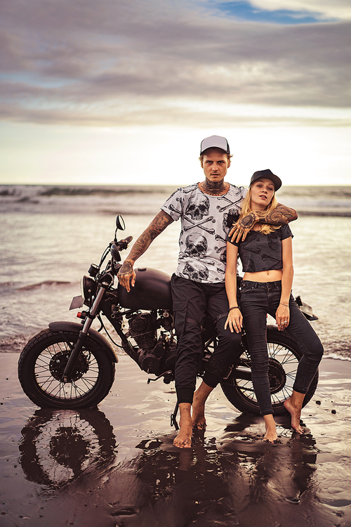 handsome boyfriend hugging girlfriend near motorcycle on ocean beach and they 