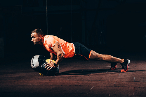 attractive athletic sportsman doing push ups on medicine ball in dark gym