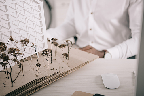 cropped image of african american architect sitting near architecture model on tabletop in office