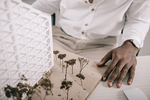 cropped image of african american architect sitting near architecture model on table in office