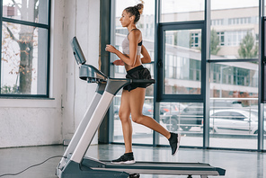 side view of african american sportswoman running on treadmill at gym