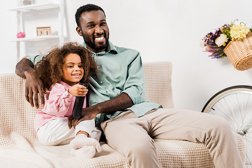 african american man and daughter watching television in living room