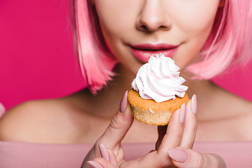 cropped view of sensual girl holding sweet cupcake isolated on pink