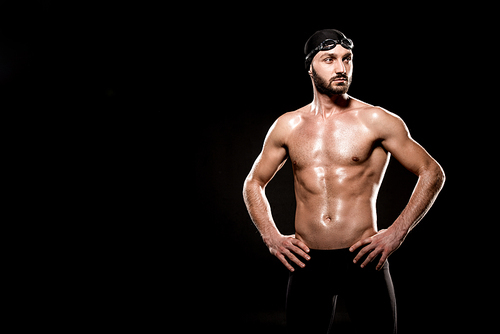 muscular swimmer standing in swimming cap and swim goggles isolated on black