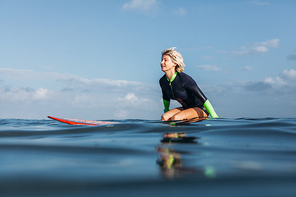 sportswoman sitting on surf board in water