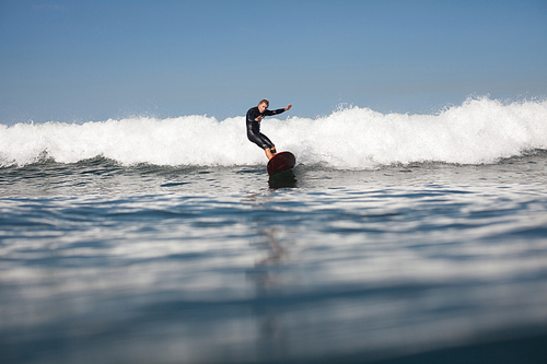 sportsman surfing wave on board in ocean