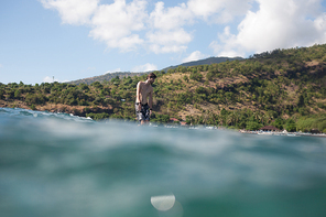 man on surf board in ocean, coastline on background