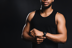 cropped shot of muscular young african american man in sportswear standing isolated on black