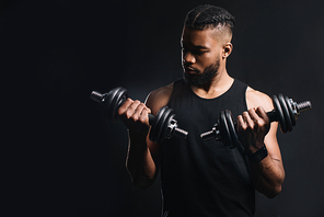 handsome muscular african american man exercising with dumbbells isolated on black