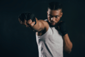 close-up view of young african american kickboxer training on black