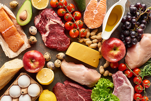 Top view of assorted meat, poultry, fish, eggs, fruits, vegetables, cheese, olive oil and baguette