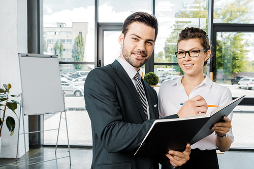 portrait of smiling businessman signing papers with colleague near by  in office