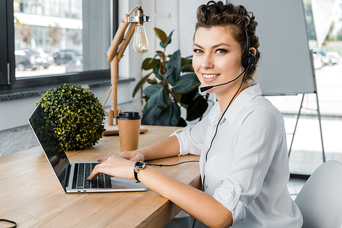 young smiling female call center operator with headset at workplace in office