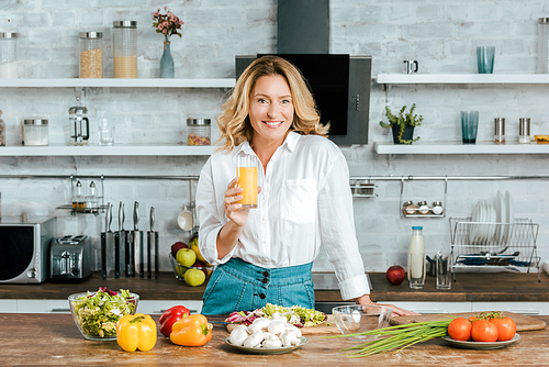 beautiful adult woman drinking orange juice while cooking at kitchen and 