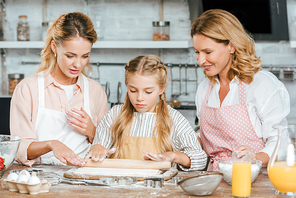 little child learning to make dough with mother and grandmother at home