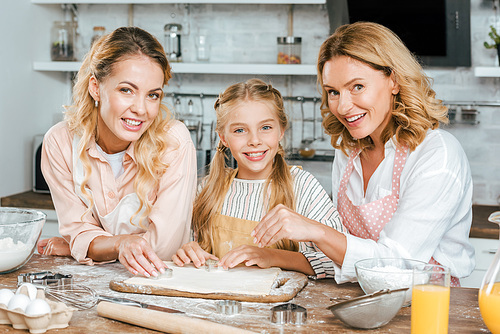beautiful happy three generations of women making dough together at home and 
