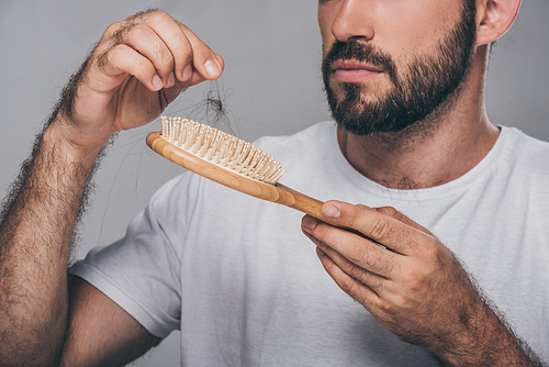 cropped shot of bearded man holding hairbrush, hair loss concept