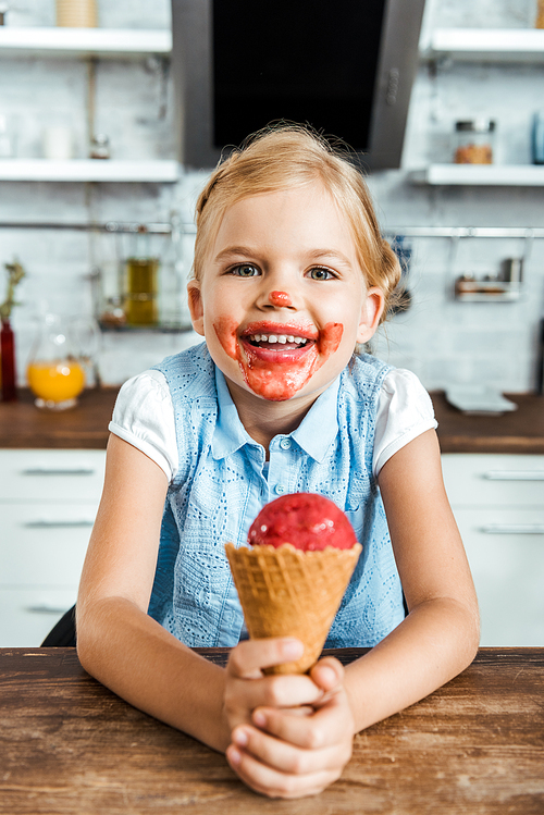 adorable happy child holding delicious ice cream cone and smiling at camera