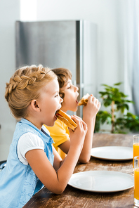 side view of cute little children eating tasty sandwiches