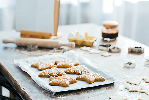 close-up view of delicious ginger cookies on baking tray, cookbook and ingredients on table