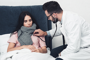 doctor listening breath of female patient while she lying in bed