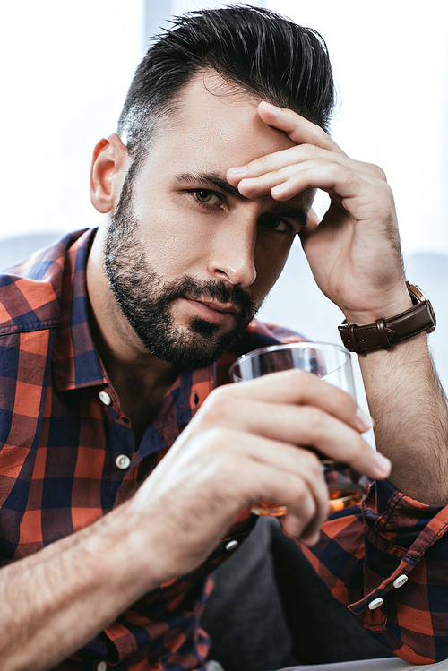 close-up portrait of depressed young man with glass of whiskey 