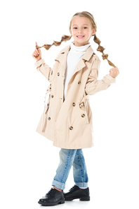 adorable blonde kid with braids posing in beige coat, isolated on white