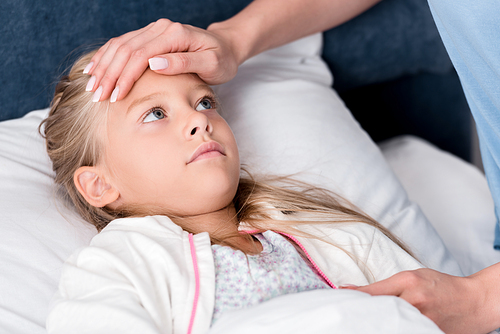 cropped shot of mother checking daughters temperature with hand