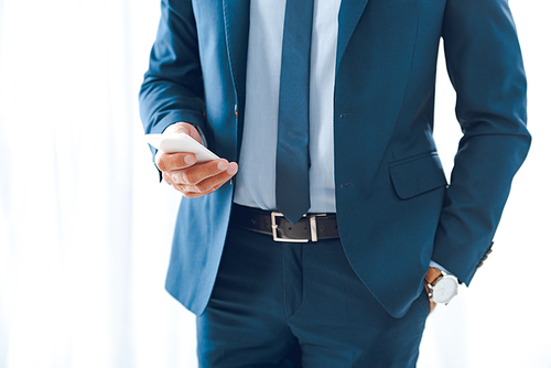 cropped shot of businessman in formal wear using smartphone