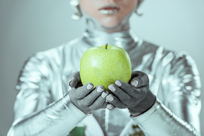 close-up partial view of cyborg holding green apple isolated on grey, future technology concept