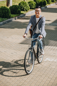 handsome smiling asian man cycling on bike in city