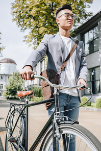 handsome asian man walking with bike in city