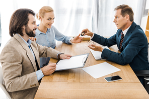 insurance agent giving key to woman while man signing papers