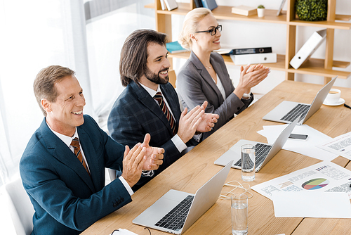 happy business people clapping hands at meeting in office