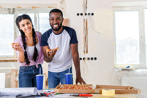 happy african american couple having lunch with pizza and soda during renovation at home