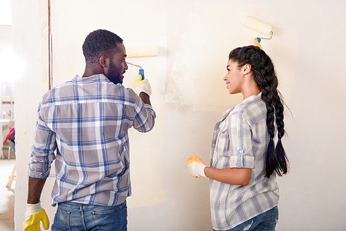 young happy couple painting wall while making renovation of home