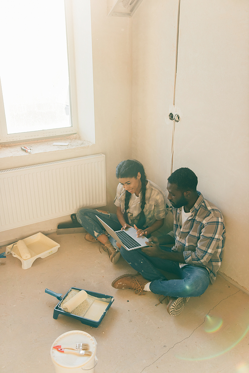 high angle view of african american couple resting with laptop during renovation of new home
