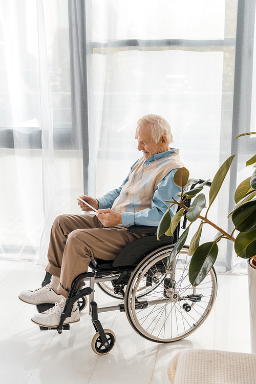 senior smiling man sitting in . and using digital tablet in nursing home