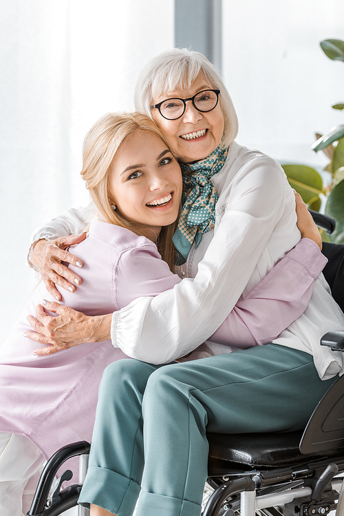 young cheerful woman hugging senior woman in .