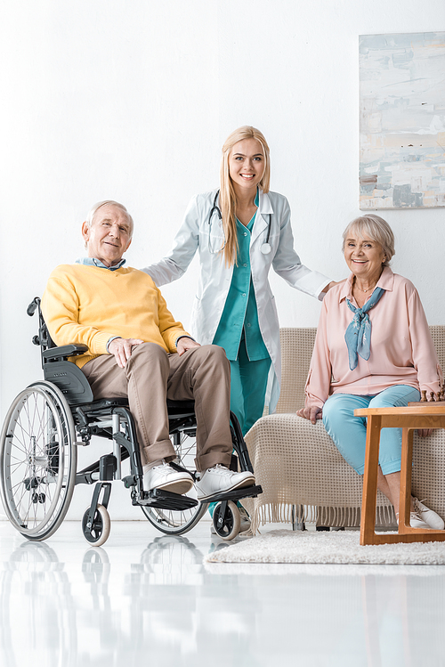 young cheerful female doctor talking to senior people at nursing home