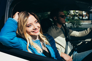 smiling woman looking out car window while boyfriend driving car