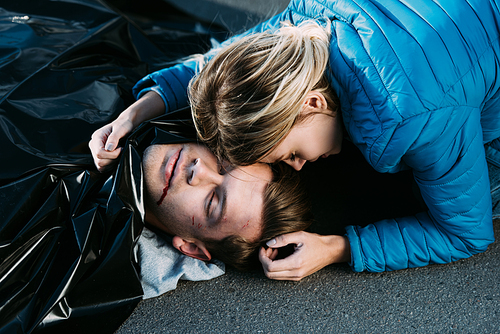 young woman crying and hugging dead man on road