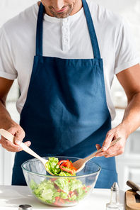 cropped view of man mixing salad at kitchen
