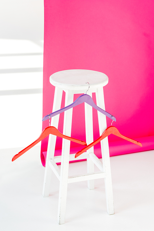 multicolored painted hangers with white wooden chair and pink wallaper
