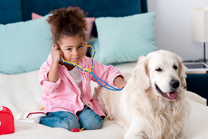Adorable african american child playing with stethoscope and retriever