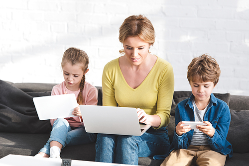 mother and beautiful children using digital devices at home